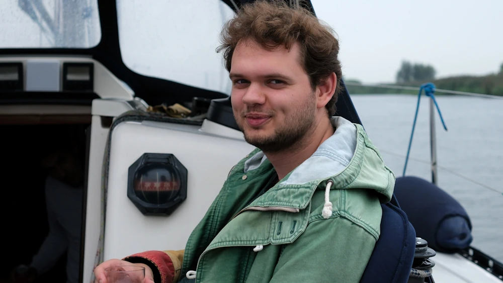 Rayo sitting on a sailing boat smiling at the camera